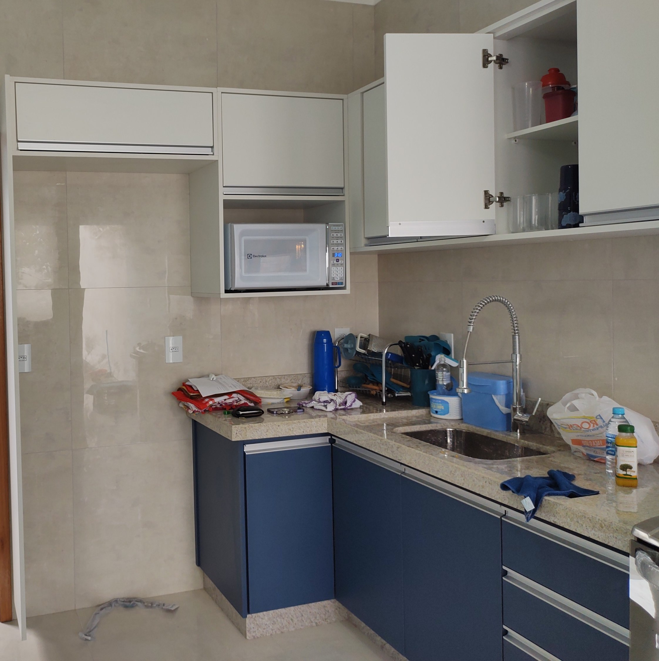 Cozinha entregue com armários planejados em azul e branco, bancada de granito e cuba embutida