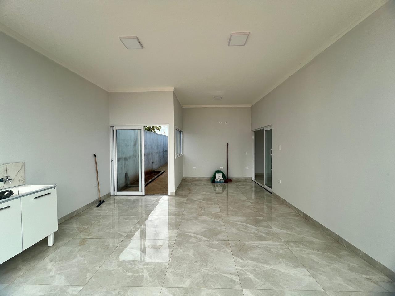 Sala ampla de casa entregue, com porcelanato polido e porta de vidro para a área externa