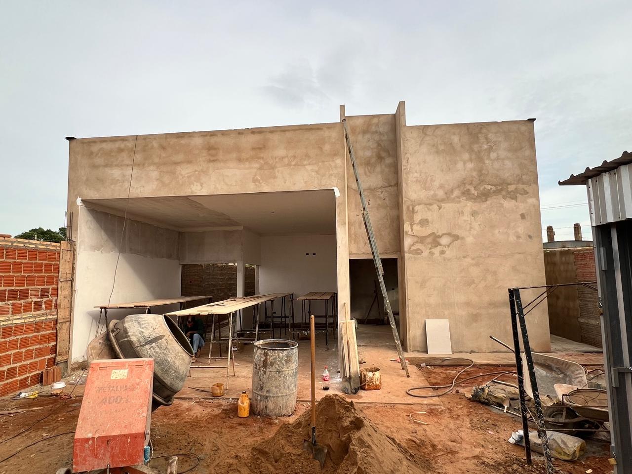 Área interna em obra com contrapiso, cavaletes de trabalho, betoneira e material de acabamento