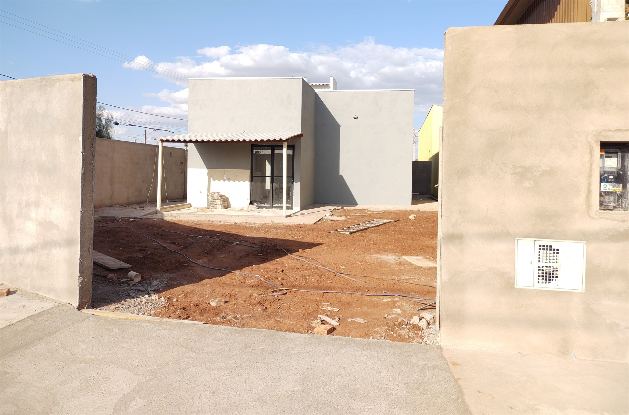 Quintal em preparação nos fundos da casa, com terra exposta e instalações à vista